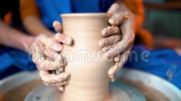 年轻情侣的手在陶工的车轮上做泥壶浪漫约会中人们的性感镜头陶器视频的预览图