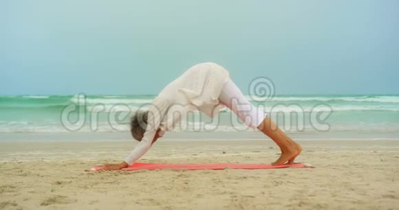 活跃的非洲裔美国老年妇女在海滩上练习瑜伽的侧视图视频的预览图