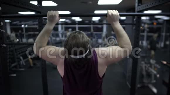 男人试图拉起他沉重的身体增加肌肉力量在健身房锻炼视频的预览图