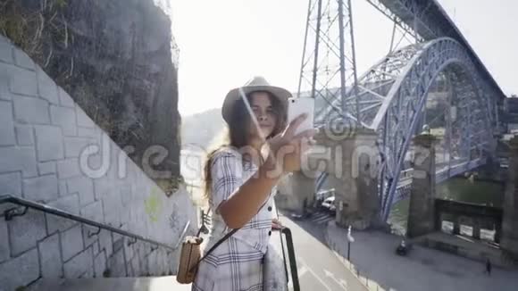 戴帽子的女士在堤岸的智能手机上自拍视频的预览图