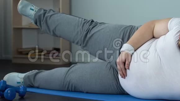 肥胖男性在家中躺在垫子上做腿部运动减肥马拉松运动视频的预览图