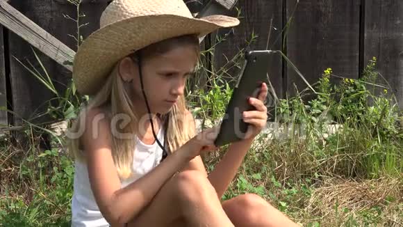 乡村小女孩在4K自然放松的乡村女孩户外玩平板电脑视频的预览图