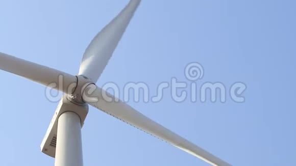靠近一个白色转子的风力发电机的正面背景上有一个晴朗的蓝天视频的预览图