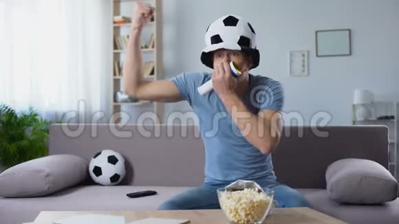 戴着球迷帽的足球球迷吹着号角欢呼着点球得分视频的预览图