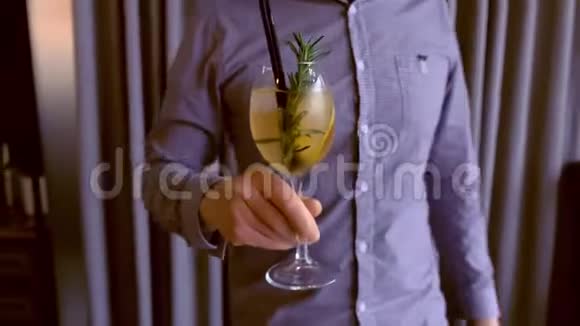 巴曼在酒杯里端着一杯酒鸡尾酒里面有起泡葡萄酒冰和酒放在桌子上双手特写视频的预览图