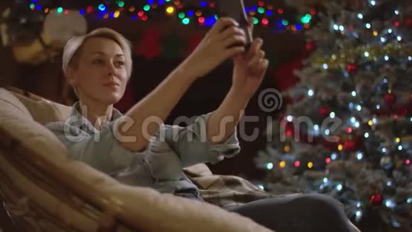 在圣诞夜金发女人在智能手机上自拍视频的预览图