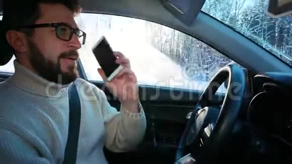 冬天一个人在城市之间的公路上开车他在说智能手机在笑视频的预览图