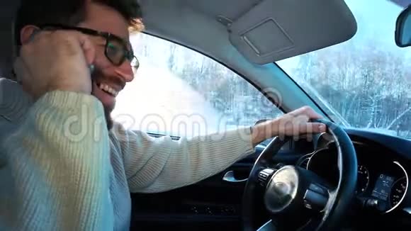 冬天一个人在城市之间的公路上开车他在说智能手机在笑视频的预览图