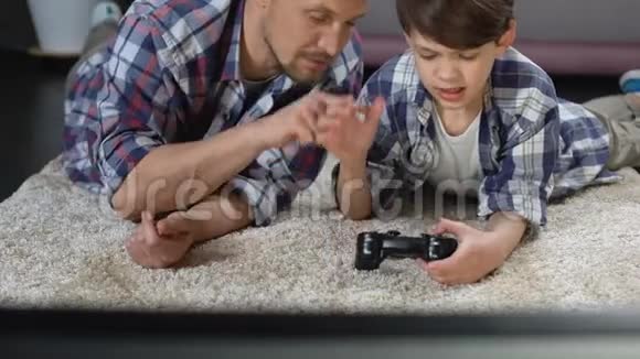 爸爸试图帮助儿子操作电子游戏操纵杆支持和照顾视频的预览图