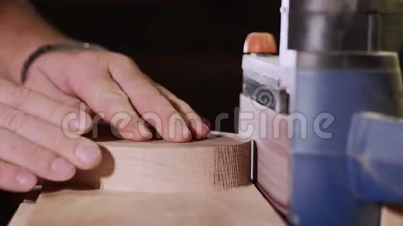 木工车间配合打磨机工作的工匠双手特写视频的预览图