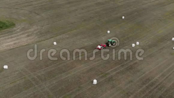 农业机械将作物卷成捆包起来用白色包装空中观景4K视频的预览图