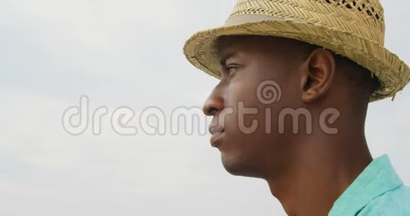 站在海滩上戴帽子的非裔美国人的侧面景色视频的预览图