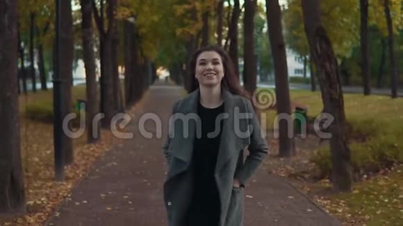 穿着外套的小女孩在秋天公园散步慢动作地微笑着视频的预览图