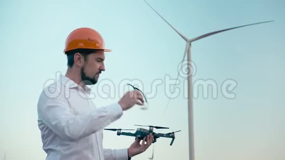 戴着橙色防护头盔和带控制面板的护目镜的白种人工程师从一个聪明的人手中起飞视频的预览图