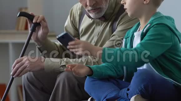 老人和孙子一起在智能手机上看视频家庭亲密视频的预览图