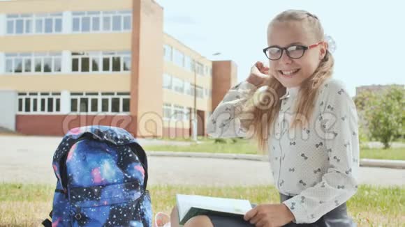 一个十一岁的女学生拿着一本书坐在草地上伸出一只手指好心情视频的预览图