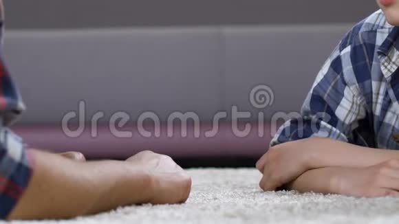 男孩手臂摔跤与父亲躺在地板上家庭联系沟通视频的预览图