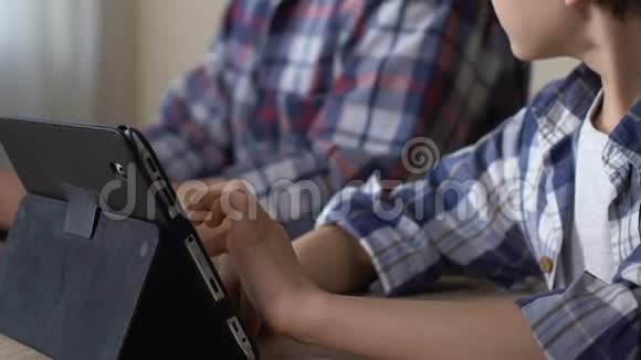 男孩使用平板电脑上网在父亲工作时玩轻松的游戏视频的预览图