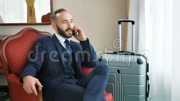 微笑的男商人时髦的西装交谈商务电话使用智能手机视频的预览图