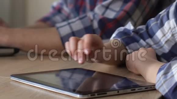 听话的孩子在平板电脑上玩手机游戏而父亲在手提电脑上工作视频的预览图