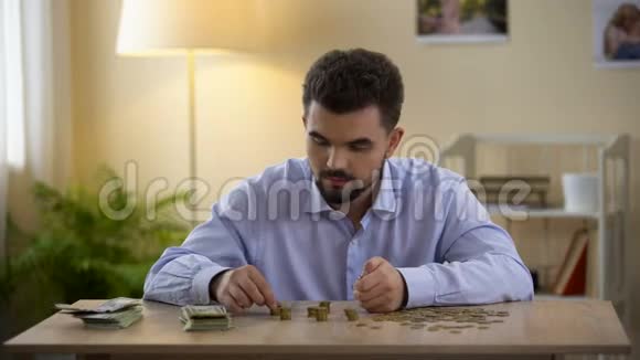 快乐的男人在家里数硬币和钞票微笑着节省预算视频的预览图
