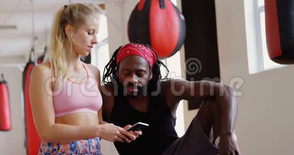 男性教练和女性拳击手使用手机4k视频的预览图