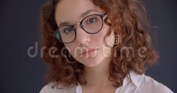 年轻的长着头发白种人卷曲的女性戴着眼镜看着背景镜头的特写镜头视频的预览图