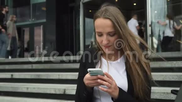 商务女性在城市大厦入口处使用智能手机人们会落后视频的预览图
