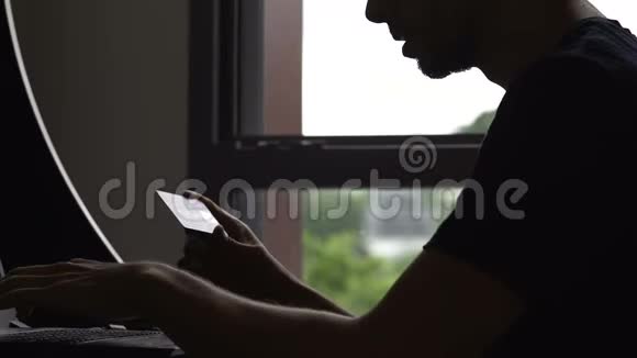 男性影子在笔记本电脑上输入卡号在线购物预订酒店视频的预览图