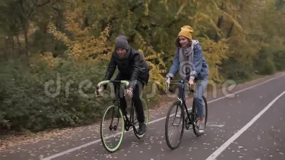 两辆自行车一对骑自行车的秋天的城市公园里浪漫的骑自行车男人和女人骑自行车积极的朋友视频的预览图