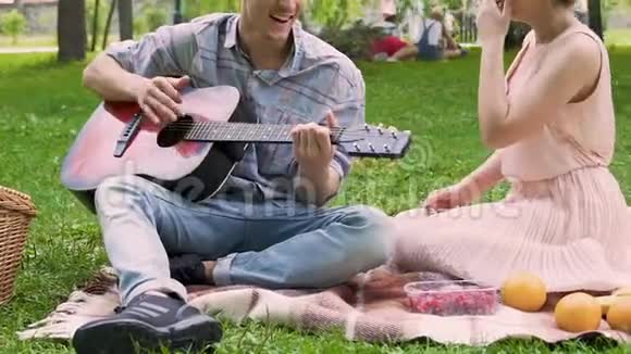 男的弹吉他和女友一起唱歌去公园野餐朋友休息视频的预览图