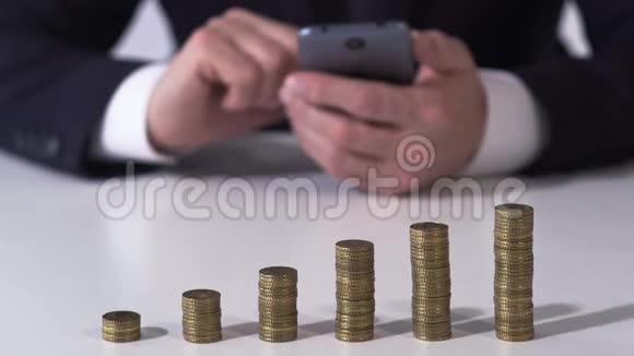 男性银行家在智能手机上使用硬币堆表检查汇率视频的预览图