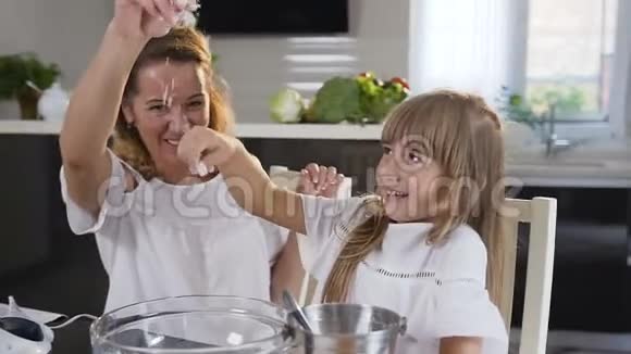 两个女孩妈妈和她的小女孩在厨房准备食物一个甜点给家人当他们学会做饭的时候视频的预览图