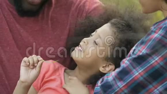 父亲用爱抚摸孩子的脸家人在公园度假放松有趣视频的预览图