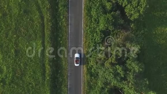空中拍摄白色敞篷车骑过空的乡村道路四位年轻的无法辨认的女性视频的预览图