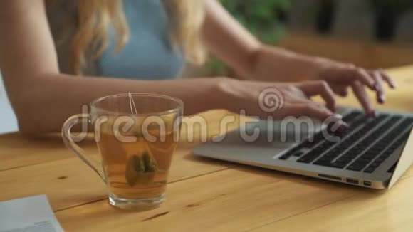一个女人用热水把茶袋浸入杯子里的特写镜头年轻的女人喝茶紧紧抓住女孩手视频的预览图
