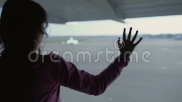 女人伤心地透过机场窗思念家乡离别留恋视频的预览图