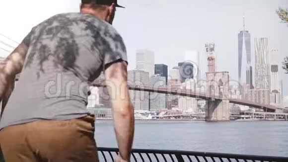 快乐的男性旅行者跑到史诗般著名的布鲁克林大桥河岸栅栏天际线纽约市欢快地跳跃视频的预览图
