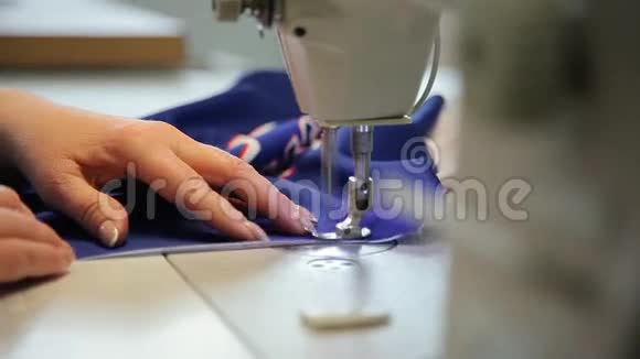 女手握着缝纫机后面的布料缝纫机后面的裁缝工作时的裁缝视频的预览图