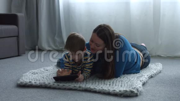 可爱的孩子和妈妈带着平板电脑在家放松视频的预览图