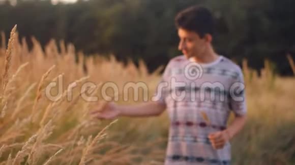 男人户外少年男孩快乐微笑享受自然举手阳光下的田野秋天免费快乐视频的预览图