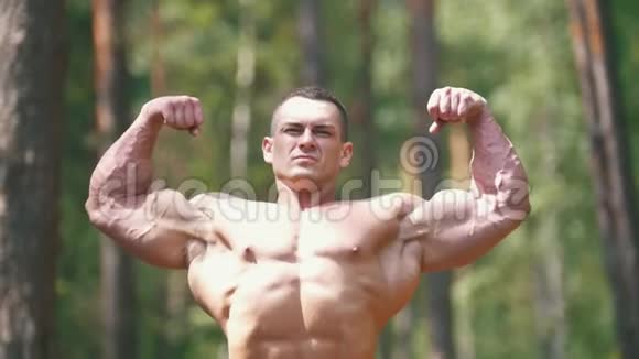 充气男子在夏季森林里锻炼巨大的二头肌视频的预览图