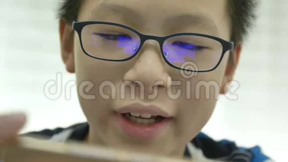 关闭年轻的亚洲男孩在智能手机上玩游戏与反射蓝盒眼镜视频的预览图