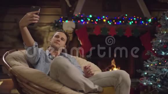 圣诞夜年轻的帅哥在智能手机上自拍视频的预览图
