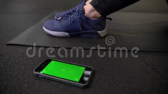 这款手机的绿色屏幕颜色鲜艳躺在健身房的Karrimat运动鞋附近视频的预览图