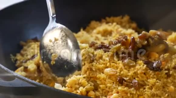 一个的手在皮拉夫的背景上用一个大勺子一大罐皮拉夫用不同的糙米煮熟视频的预览图