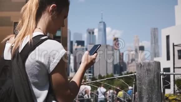 美丽的高加索女孩困惑地看着智能手机附近惊人的曼哈顿金融中心全景纽约市视频的预览图