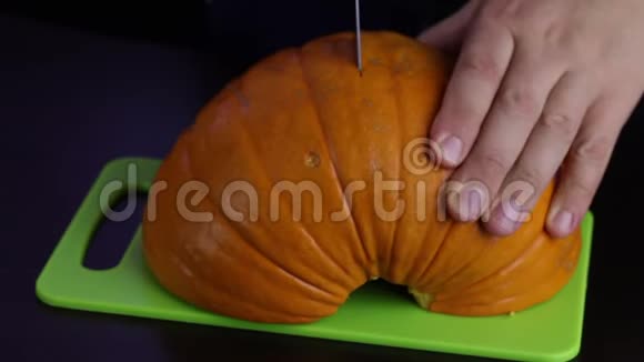 一个人用刀子在切割板上切南瓜南瓜是橙色的世界素食日视频的预览图