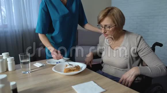 女护士帮助残疾老太太吃饭医疗支持和护理悲伤视频的预览图