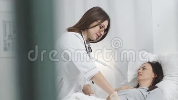 女医生带着手套在医院里摸了摸病人的腹部视频的预览图